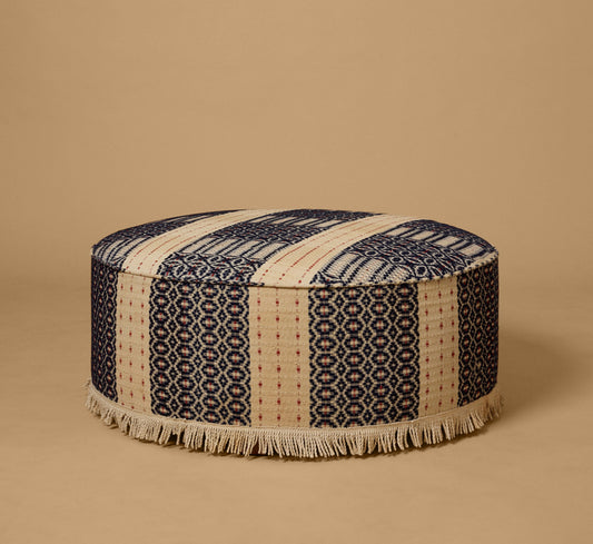 PIERCE & WARD CIRCLE OTTOMAN IN ANTIQUE AMERICAN COVERLET WITH FRINGE